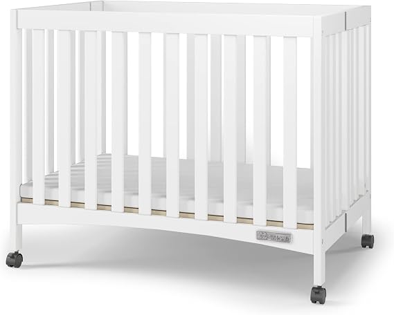 Child Craft London Mini Compact Folding Portable Crib with 2 Crib Mattress and 2 Easy Roll Locking Wheels, Durable Pine Wood Construction (Matte White)